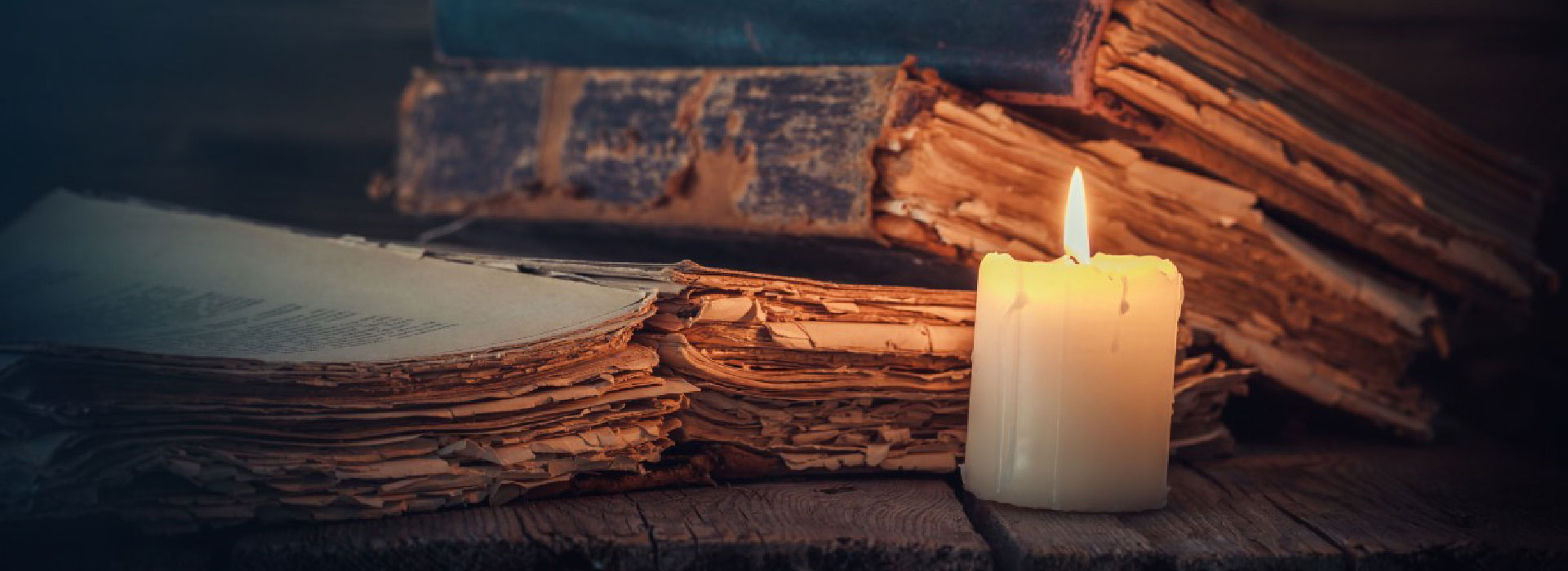 Imagem de uma vela acesa e livros atrás dela