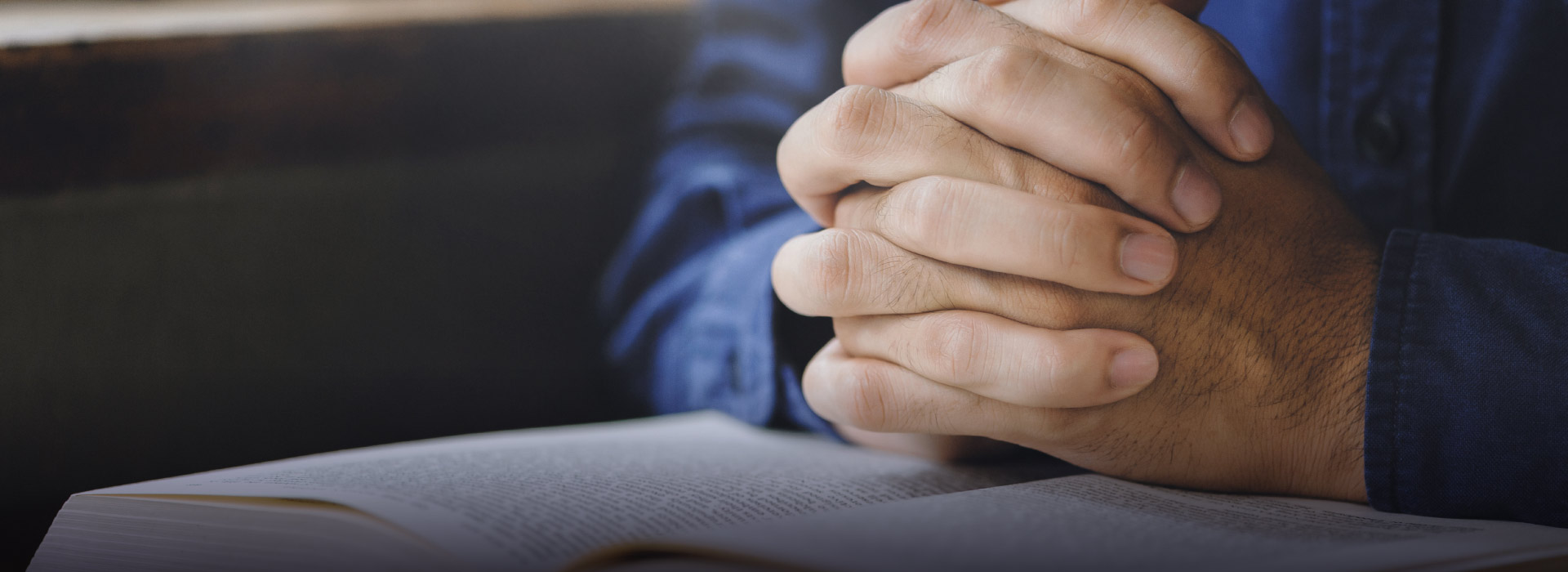 Imagem de pessoa rezando em cima de uma bíblia 